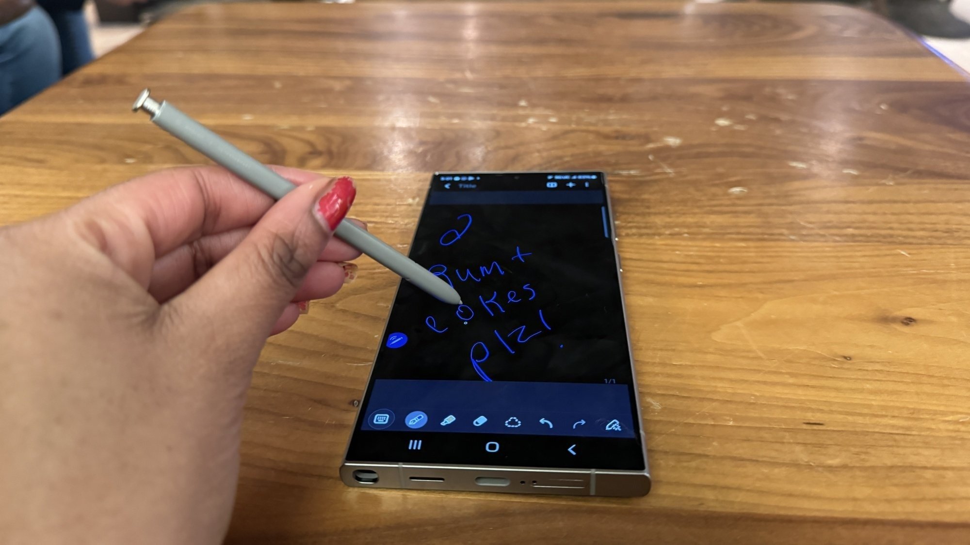 Samsung Galaxy S24 Ultra sur une table avec S Pen dans la main d'une femme