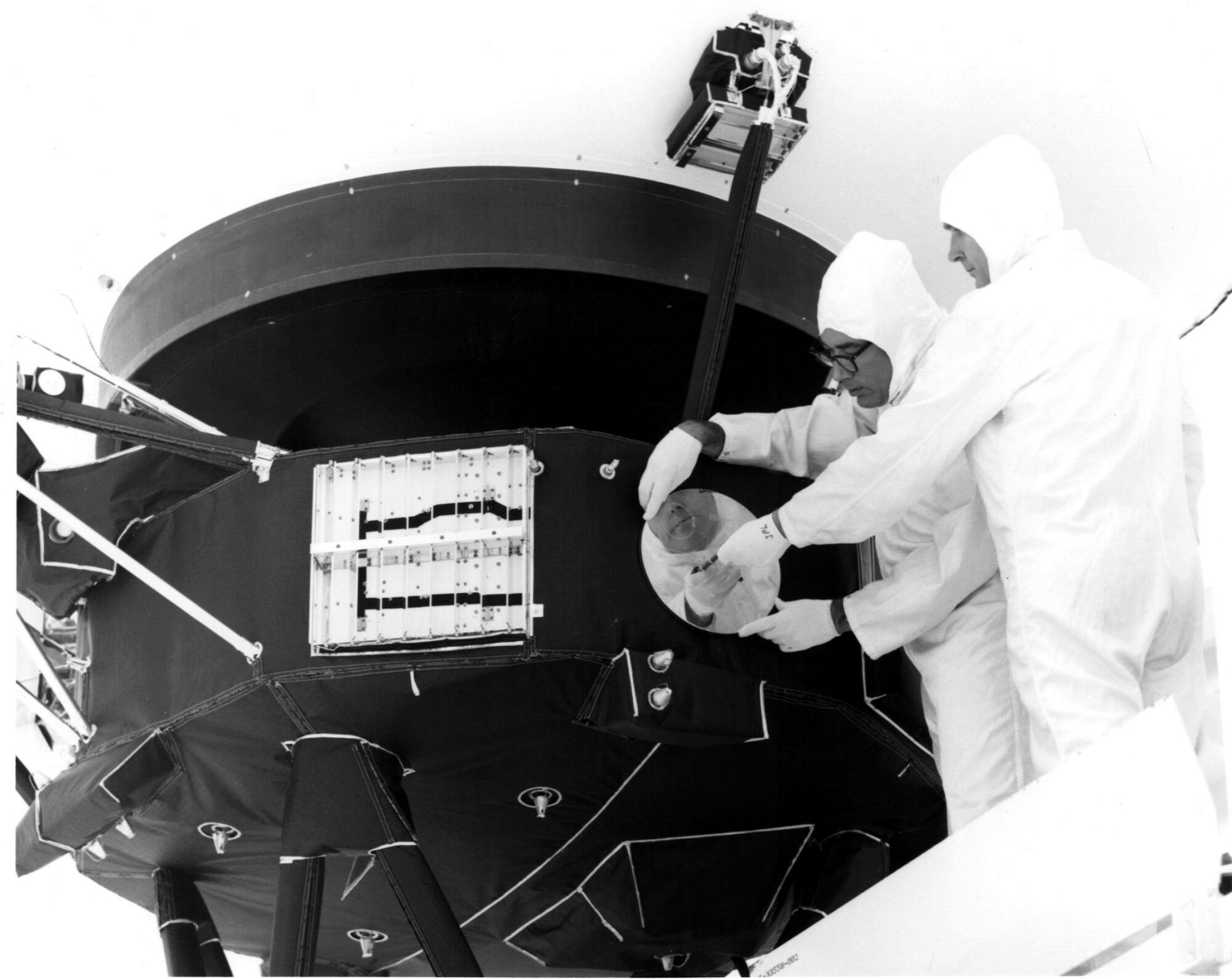 Les ingénieurs installent un disque doré – contenant de la musique, des sons et des images de la Terre – sur le côté de Voyager 1. 