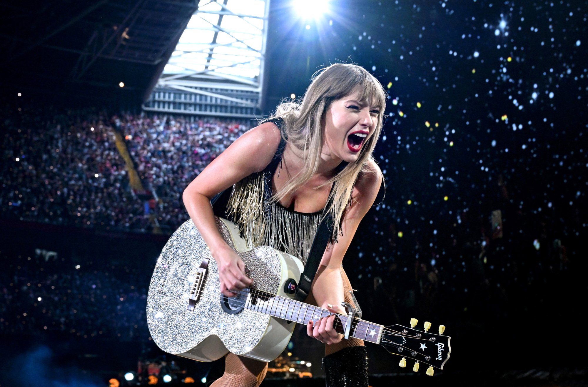 Taylor Swift jouant d'une guitare strassée, en plein concert.