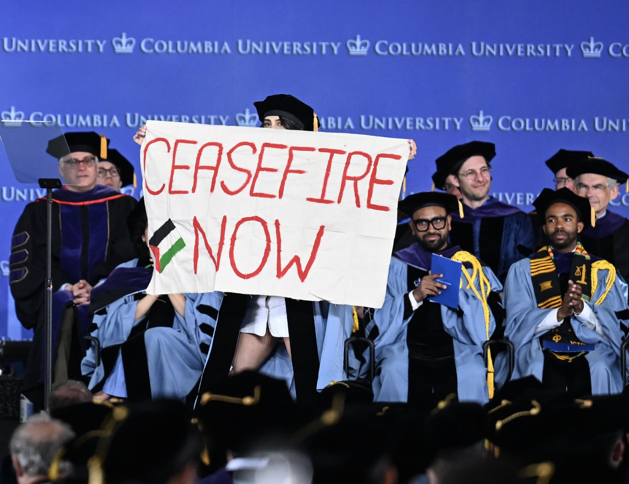 Un diplômé de l'Université de Columbia brandit une banderole « Ceasefire Now » sur la scène lors de la remise de ses diplômes.
