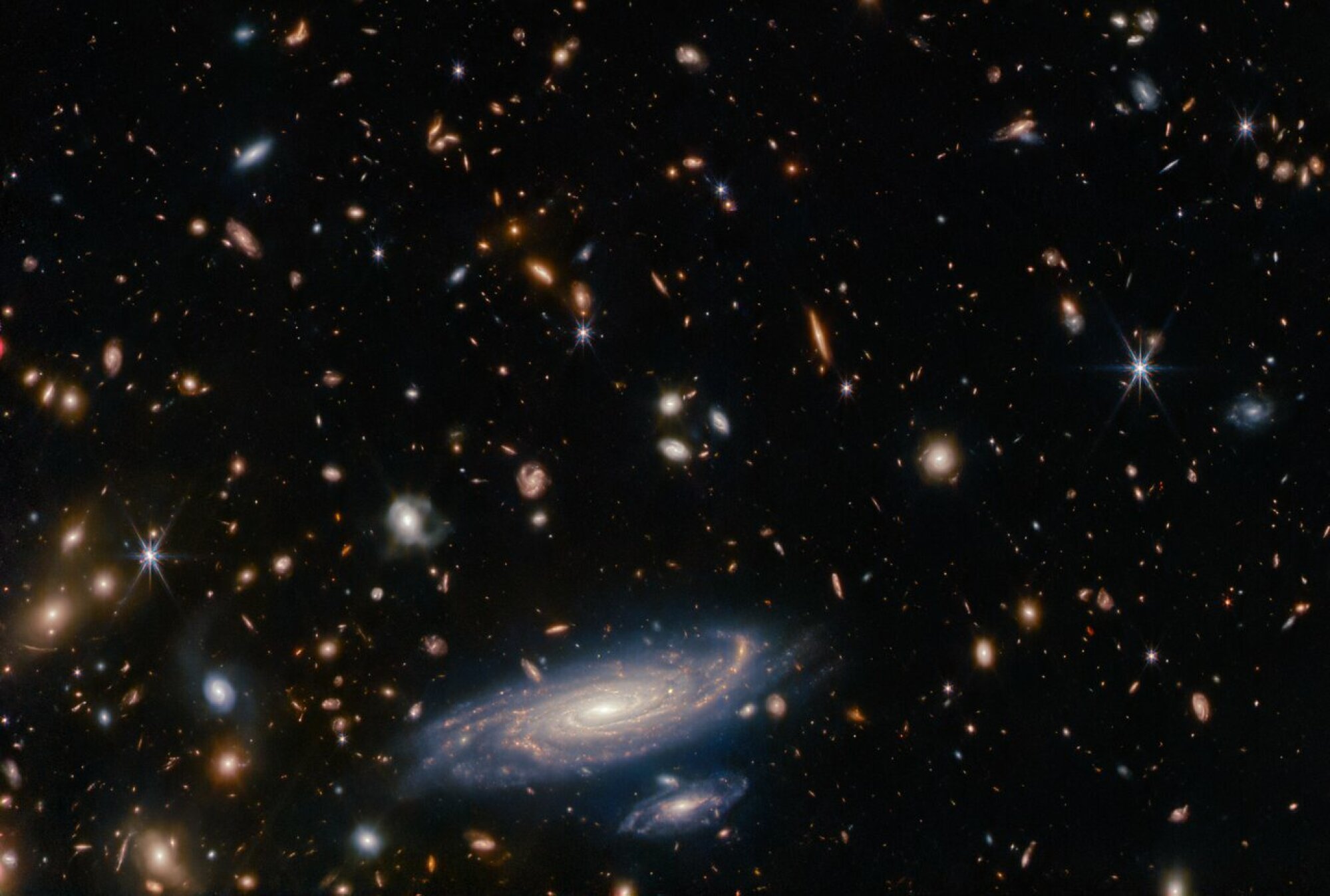 Une vue en profondeur du cosmos capturée par le télescope spatial James Webb. Chaque objet, à l'exception des étoiles à six branches au premier plan, constitue une galaxie entière.