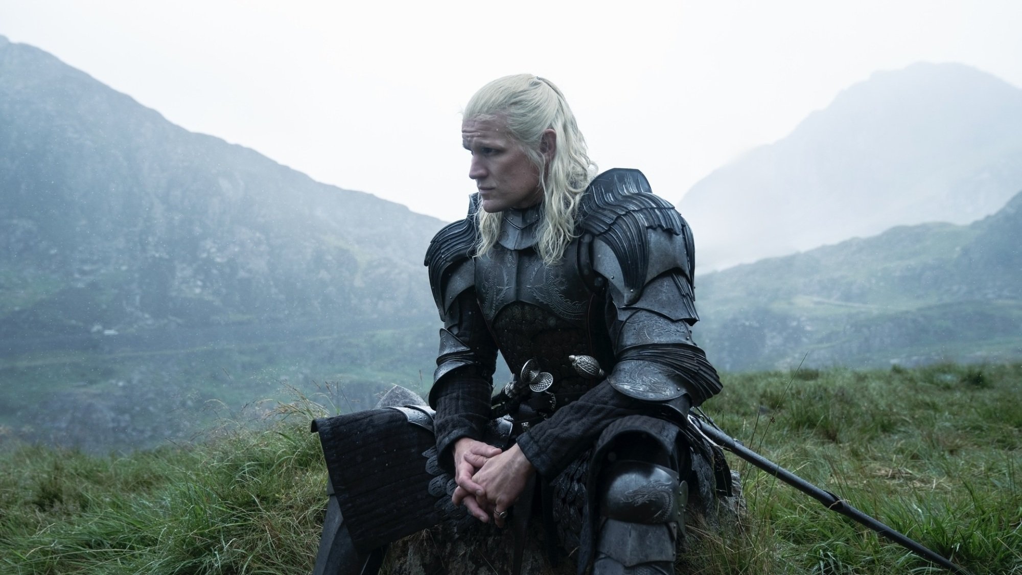 Daemon Targaryen est assis dans un champ vert en armure.