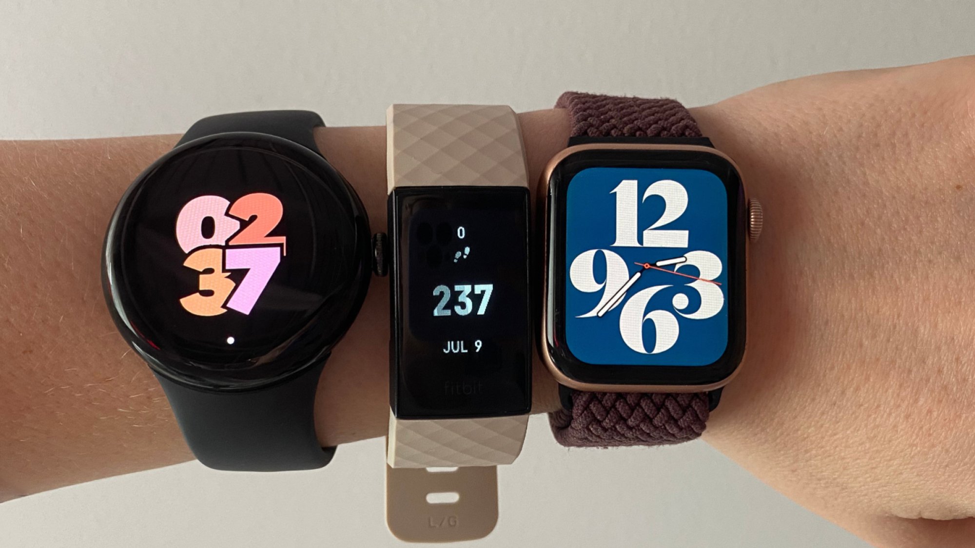 poignet d'une femme portant une montre Google Pixel 2, une Fitbit Charge 4 et une Apple Watch Series 4