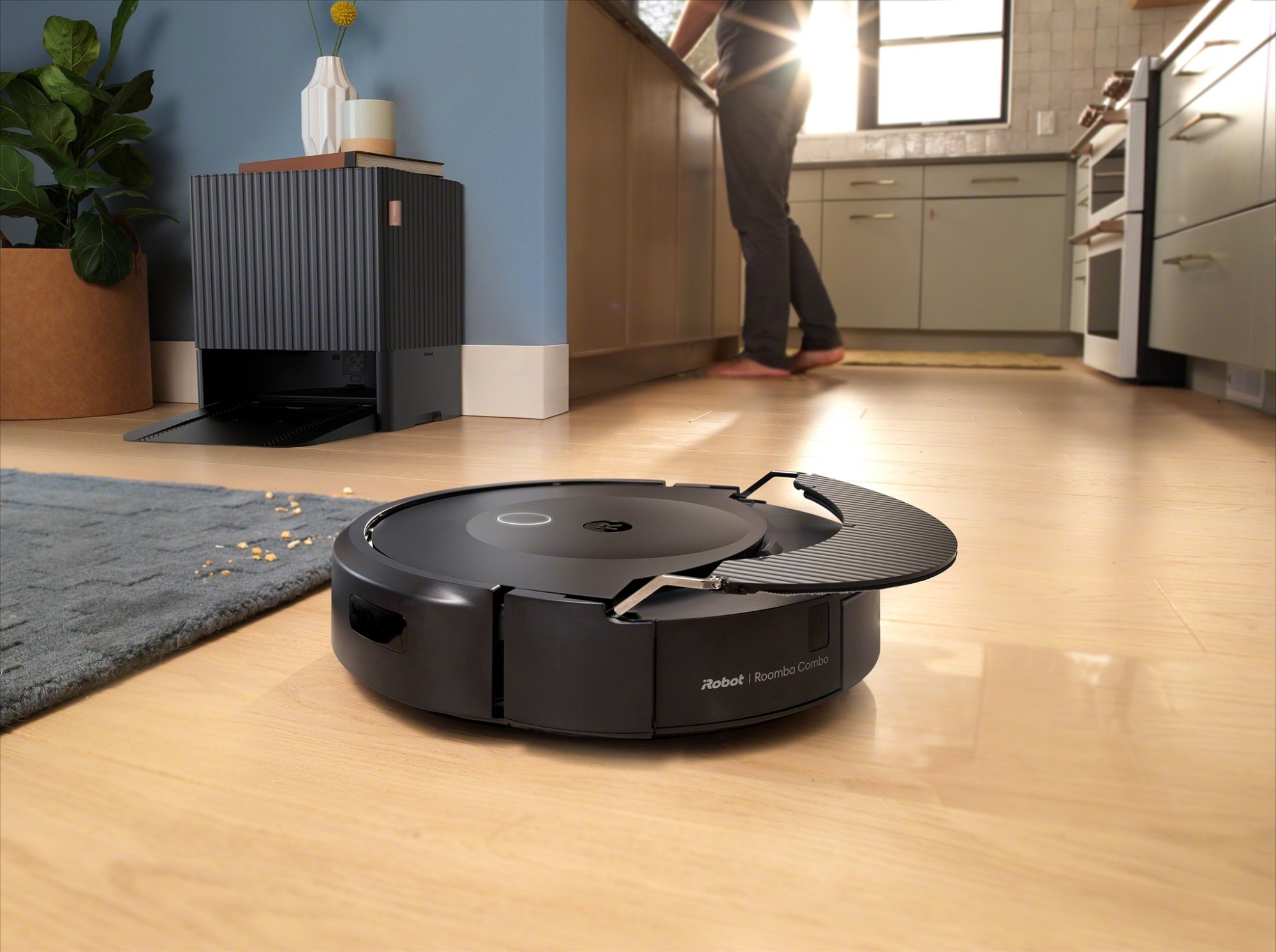 Roomba passe l'aspirateur sur un parquet en tenant une serpillère rétractable au-dessus de sa tête