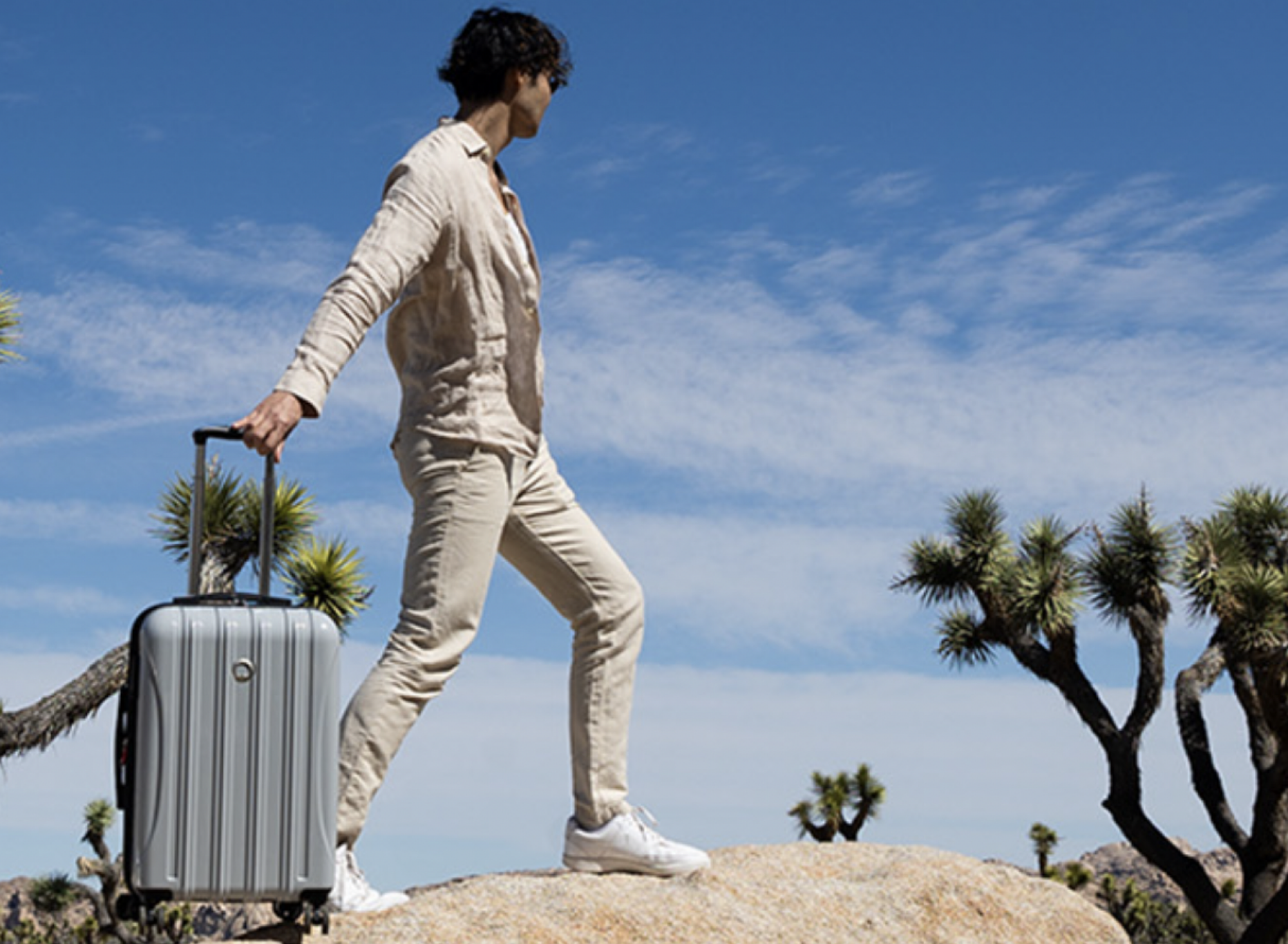 homme debout sur un rocher avec une valise