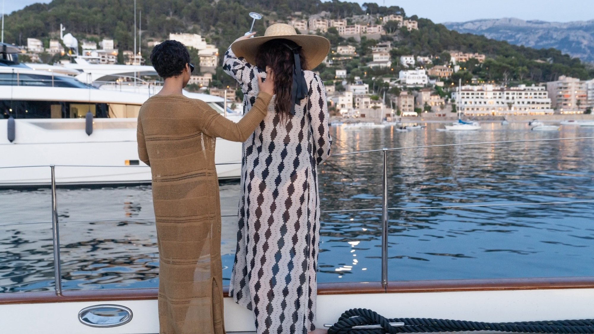 Harper et Yasmin versent du champagne dans l'océan depuis le pont d'un yacht.