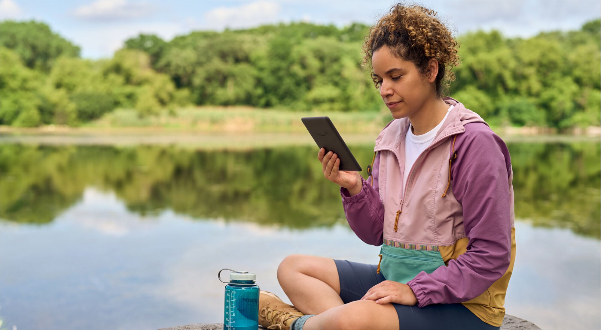 femme lisant un Kindle sur un lac