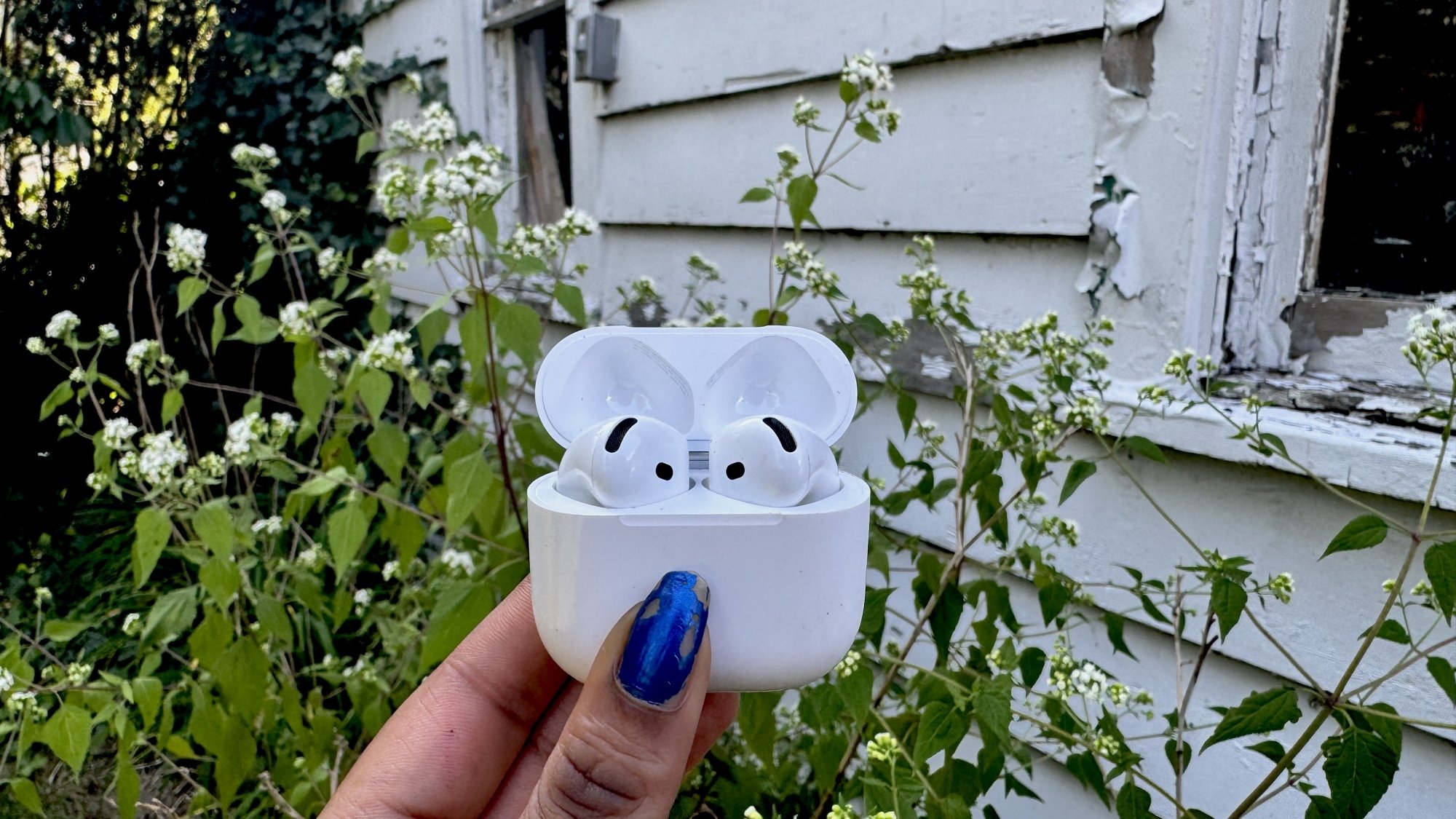 Femme tenant des AirPods 4 dans un jardin