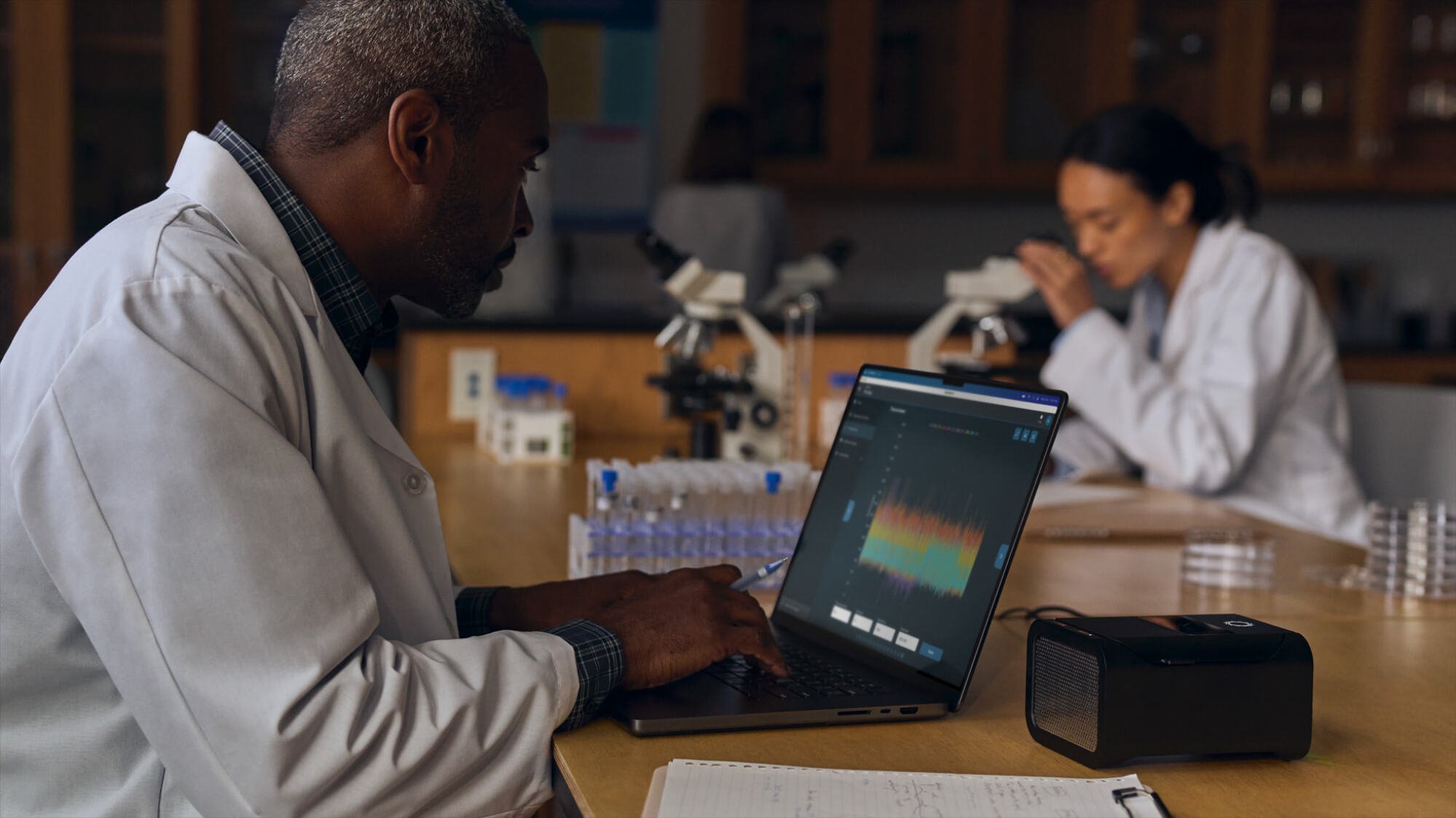 Image de style de vie du MacBook Pro M4 mettant en vedette des professionnels en blouse de laboratoire 