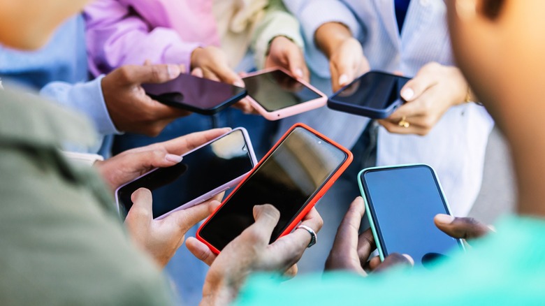 Personnes debout en cercle utilisant des téléphones