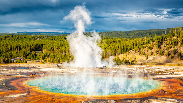 La vapeur s'élève de la source Grand Prismatic et du cratère Excelsior Geyser dans la caldeira de Yellowstone tandis que les visiteurs parcourent la promenade entre les deux.