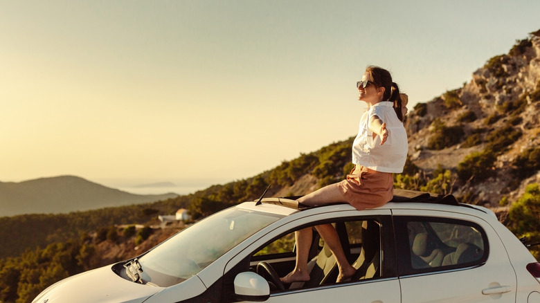 Femme relaxante au sommet d'une voiture