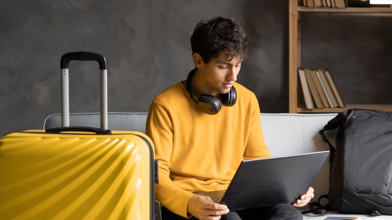 Un homme avec des bagages utilise un ordinateur portable