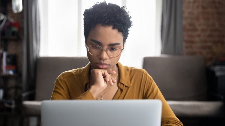 Femme pensive sur ordinateur 