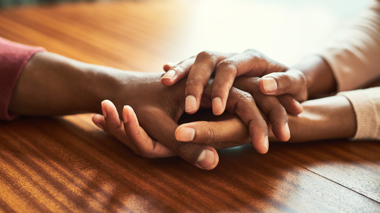 Les mains d’une femme tiennent la main d’un homme avec compassion