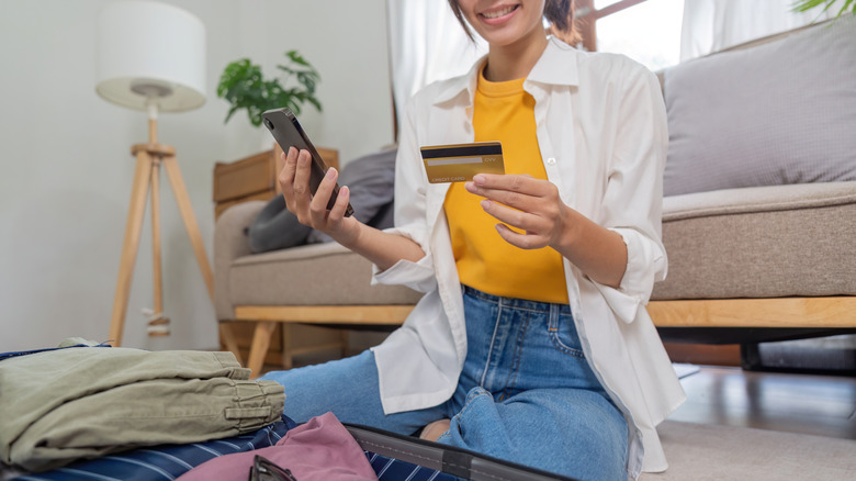 Jeune femme asiatique effectuant des achats en ligne sur son téléphone et tenant sa carte de crédit