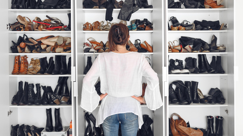 Femme regardant un placard avec de nombreuses paires de chaussures