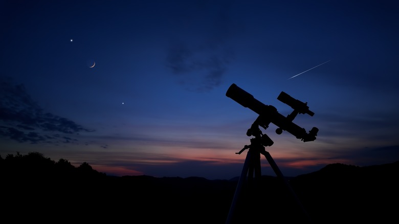 Un télescope se découpe sur un ciel étoilé au crépuscule