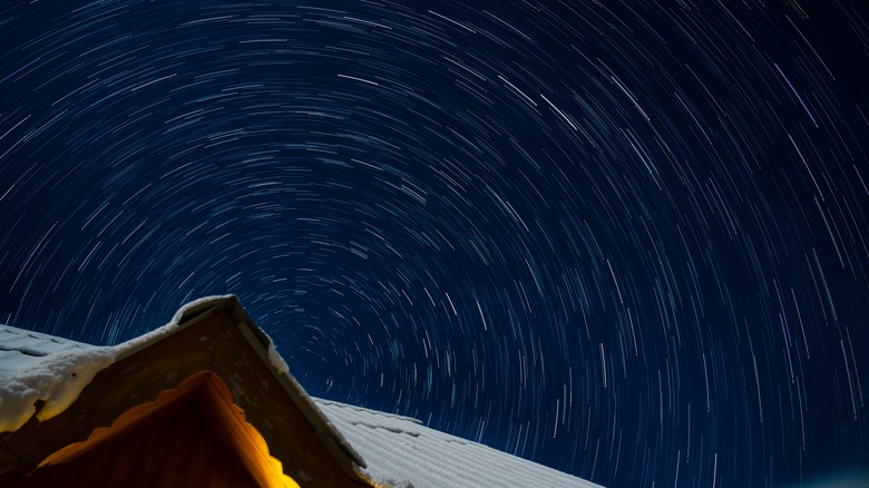 Une photo longue exposition d'étoiles la nuit dont les traînées forment un motif circulaire