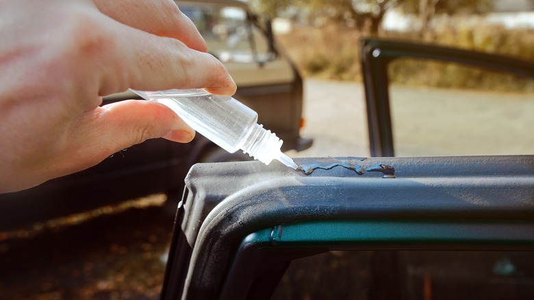 Une main appliquant un adhésif de silicone sur un joint en caoutchouc de silicone