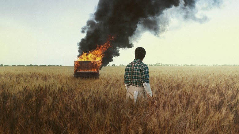 John David Washington dans le rôle de Boy Willie regarde un piano brûler dans un champ de blé dans La leçon de piano