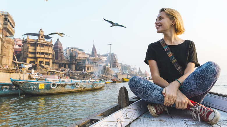 Une jeune femme est assise les jambes croisées sur un bateau en Inde