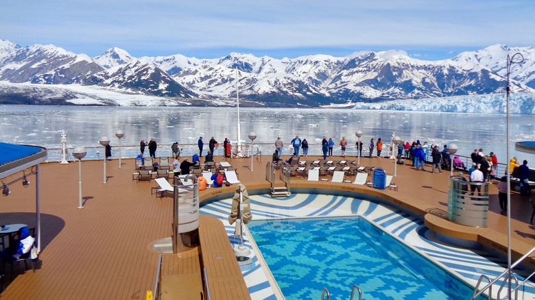 Personnes debout sur la balustrade d'un bateau de croisière, près de la piscine, surplombant les glaciers