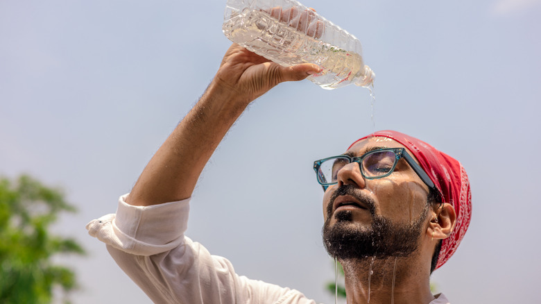 Homme versant une bouteille d’eau sur sa tête