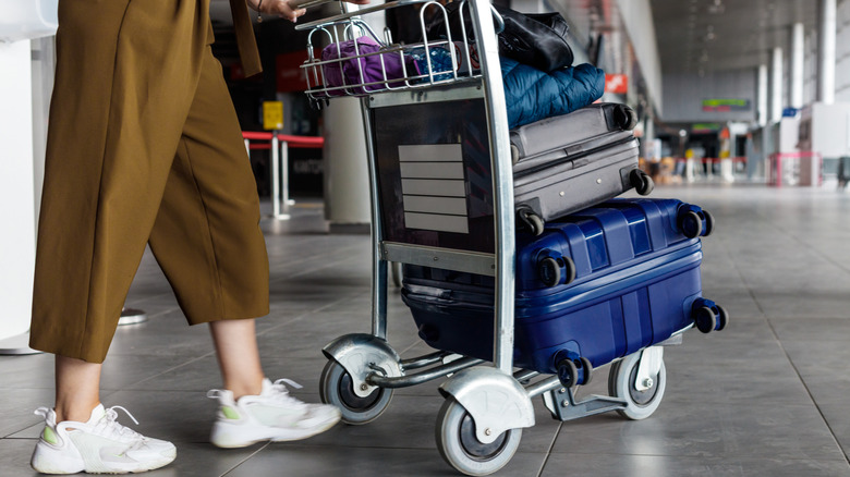 Une femme poussant un chariot à bagages dans un aéroport