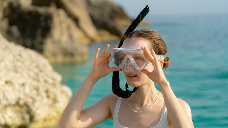 Femme portant un masque de plongée et un tube respiratoire avec fond océan délavé