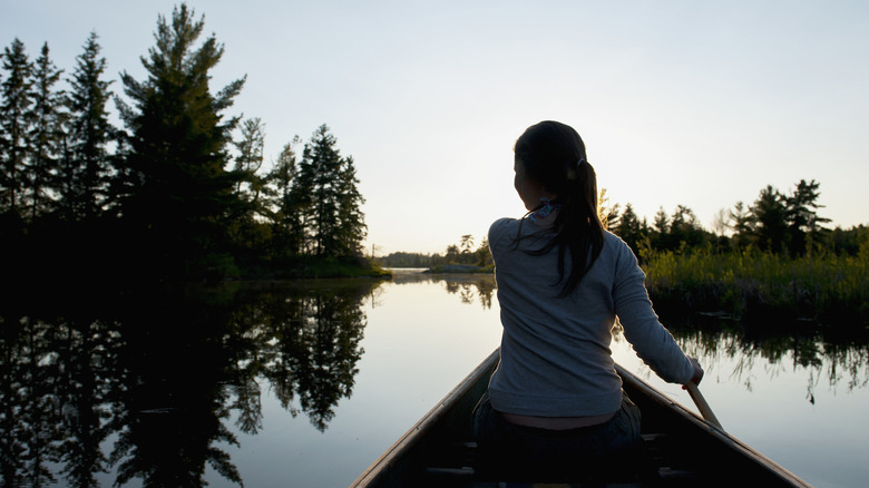 Femme faisant du canoë sur la surface lisse du lac des Bois