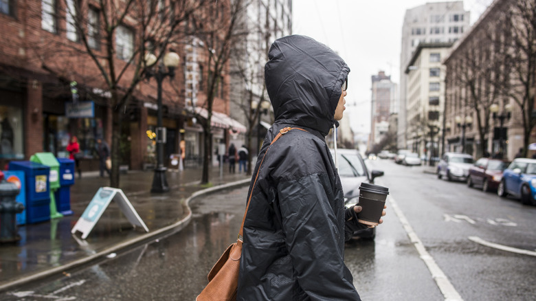 Femme en imperméable traversant une rue mouillée de Seattle