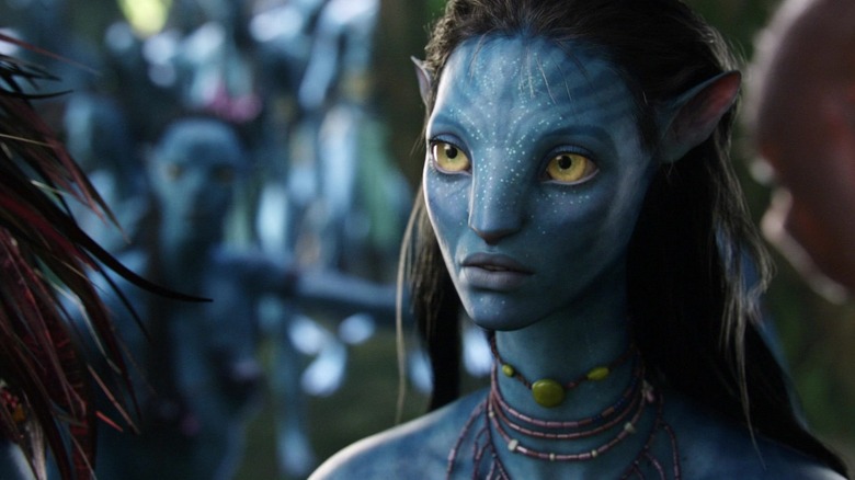 Neytiri de Zoe Saldana regarde à travers le cadre alors qu'elle parle à un autre Na'vi dans Avatar