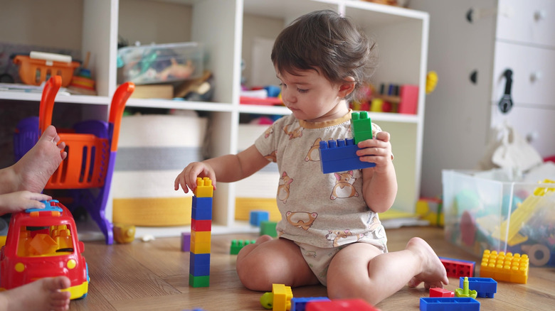 Enfant assis sur le sol et jouant avec des blocs de construction