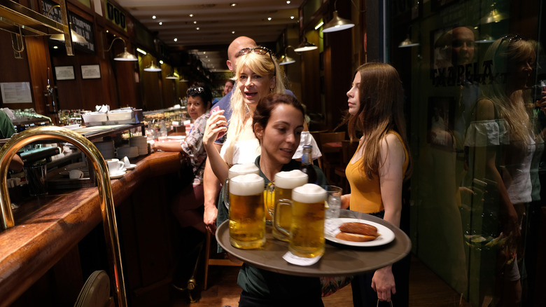 Un barman transporte trois chopes de bière dans un bar en Espagne