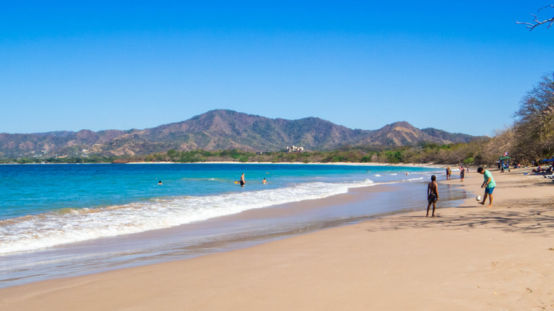 Les amateurs de plage jouent dans les vagues et le sable à Tamarindo