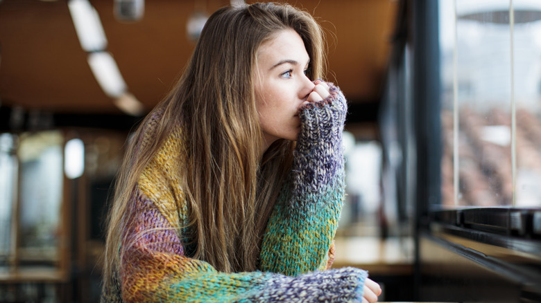 Une femme anxieuse qui regarde par la fenêtre.