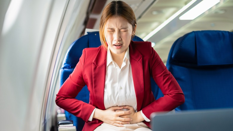 une femme avec des maux d'estomac dans un avion