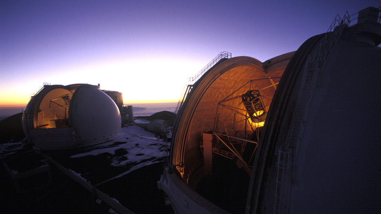 Les dômes ouverts faiblement éclairés des télescopes de l'Observatoire Keck au crépuscule avec un ciel violet au-dessus