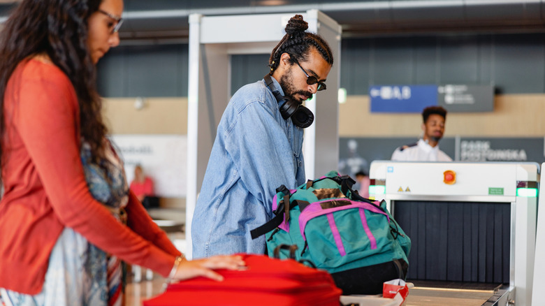 un couple prépare ses bagages pour la sécurité de l'aéroport