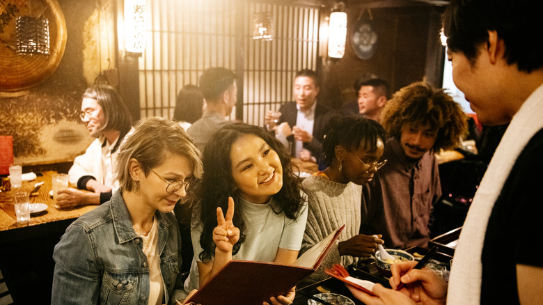 Deux femmes qui commandent de la nourriture dans un izakaya japonais occupé