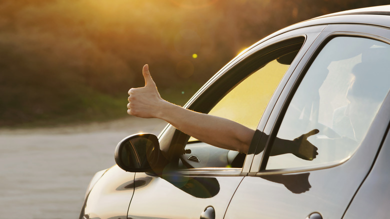 un pouce levé qui sort de la fenêtre d'une voiture