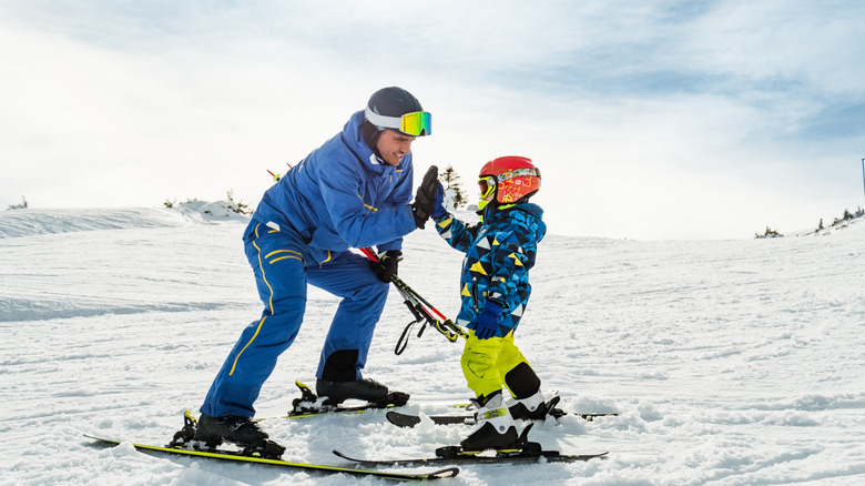 Un instructeur de ski donnant à un jeune skieur un high cinq