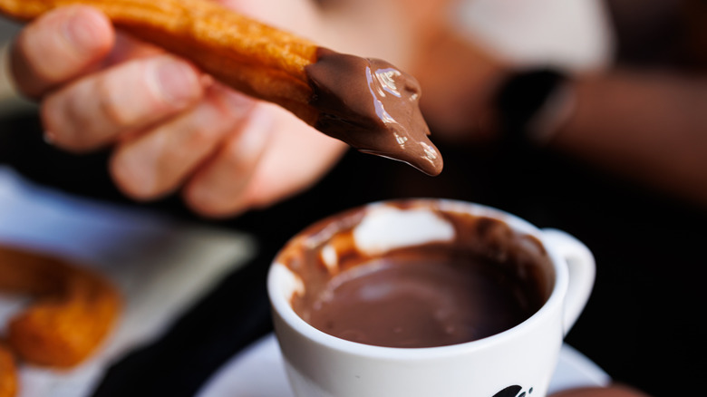 Churros trempé dans du chocolat chaud