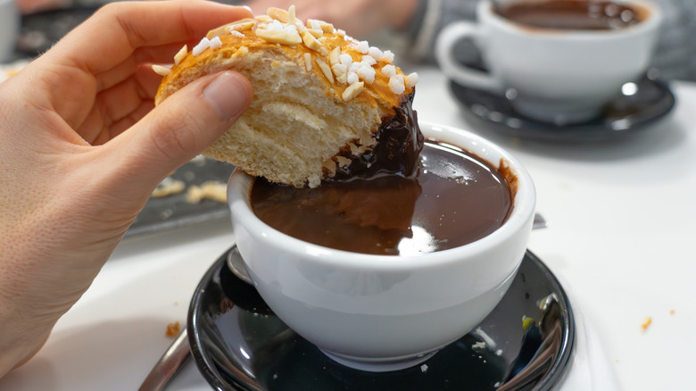 Les pâtisseries espagnoles trempées dans un chocolat chaud crémeux