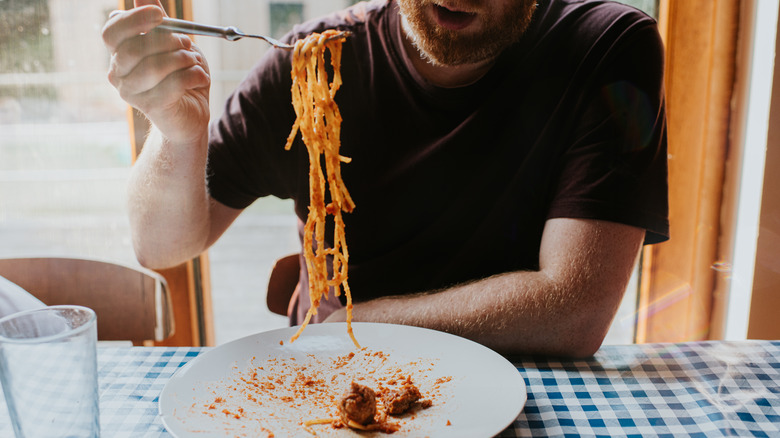 Un homme mangeant des spaghettis avec une fourchette