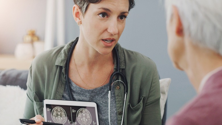 Un médecin parle à travers des images de scanneaux cérébraux avec un patient à l'hôpital