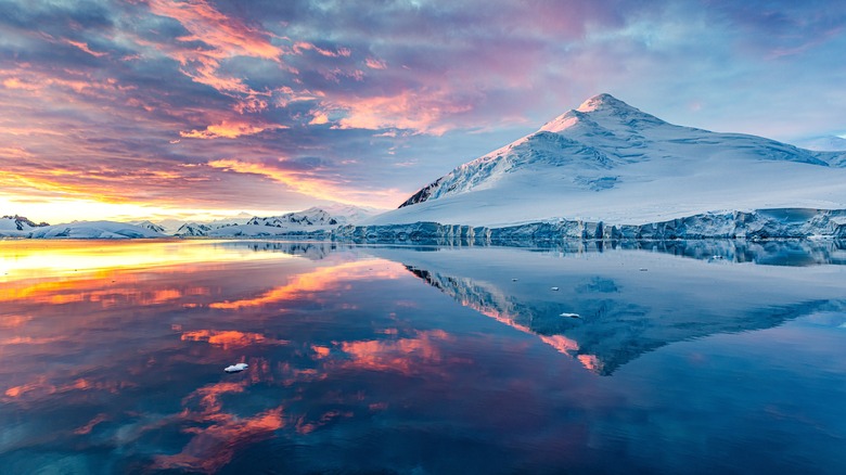 Le paysage de l'Antarctique se reflète dans l'eau au lever du soleil / coucher du soleil