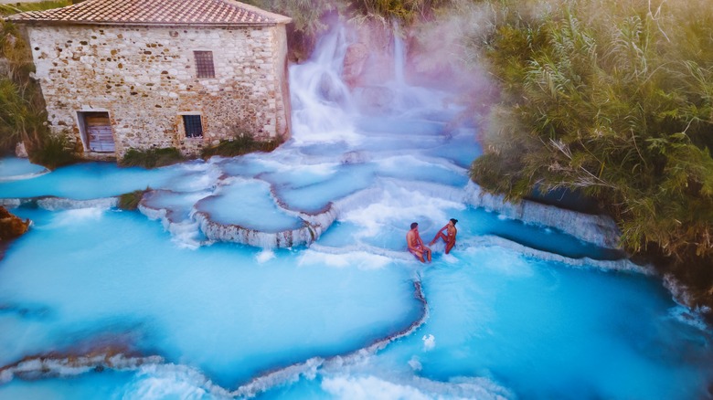 Deux personnes s'assoient près des cascades dans les sources chaudes de Saturnia d'Italie