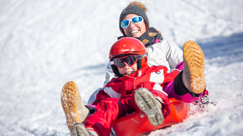 Sled de femme et enfant heureuse sur une colline enneigée